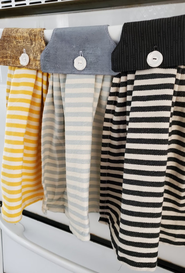 Yellow, blue and black towels hanging from an oven